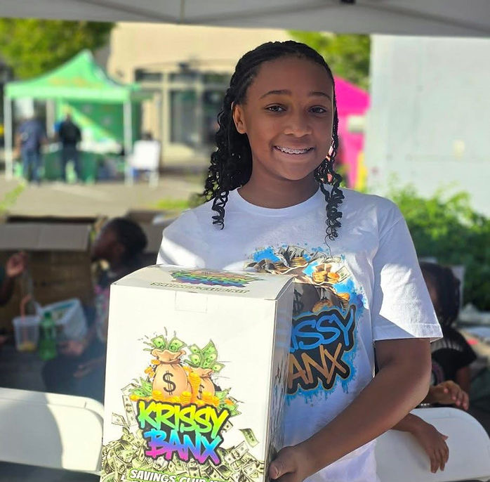 Krissy, the 13-year-old founder of Krissy Banx, holding her savings cube box at a community event